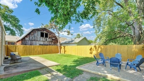 A backyard with a wooden fence, a concrete patio, and blue Adirondack chairs. - Sleeps 8 • Fenced Yard and Firepit • 8 Minutes to Louisville (Jeffersonville)