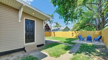 A residential property with a front door, a small porch, a fenced backyard, and outdoor seating.