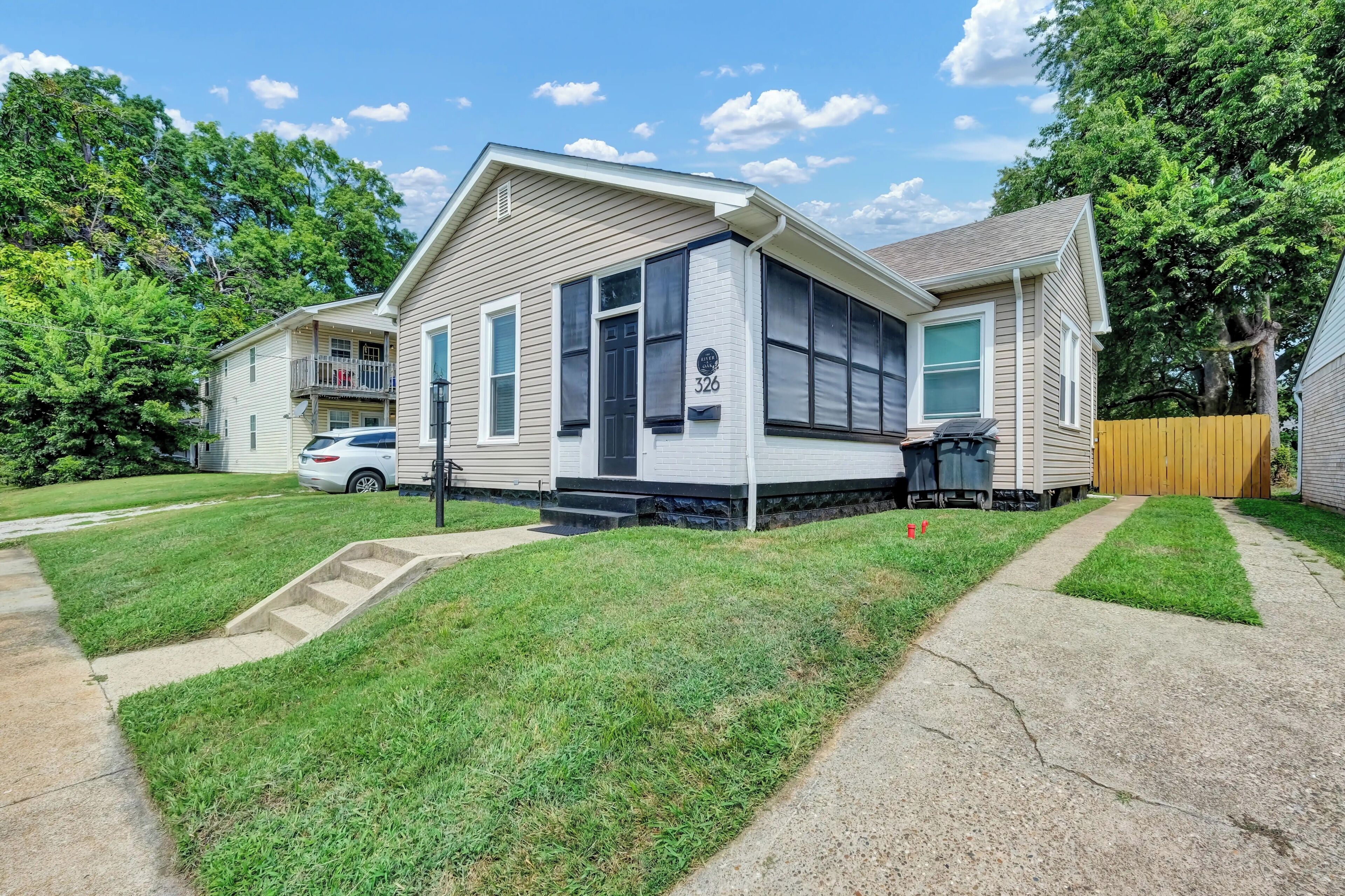 A two-story house with a front porch, a driveway, and a lawn.