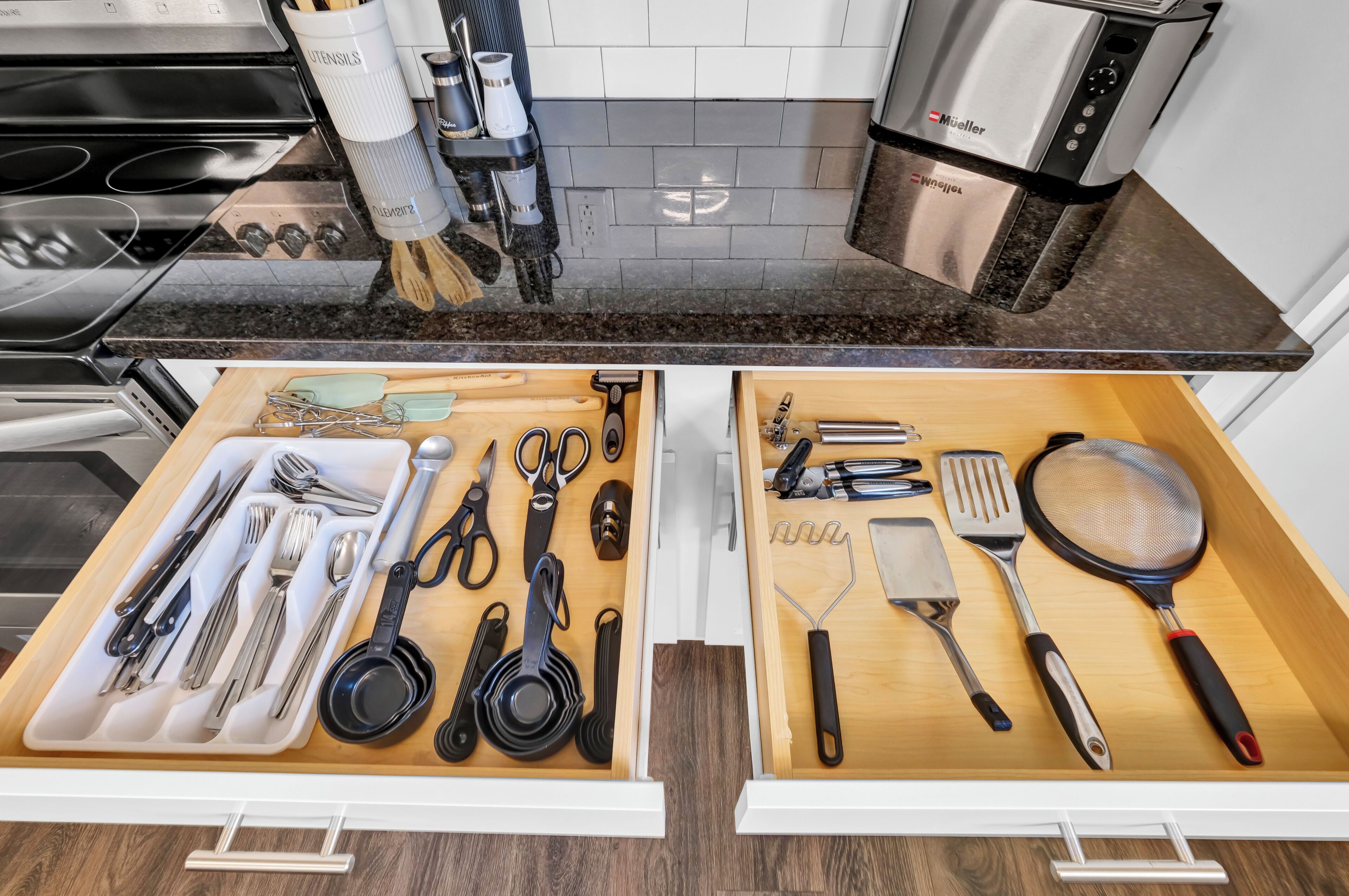 A kitchen with two drawers containing various utensils and kitchenware.