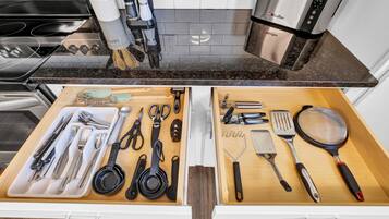 A kitchen with two drawers containing various utensils and kitchenware.