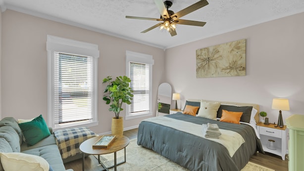 A bedroom with a bed, bedside tables, a ceiling fan, and a large window with blinds. - Sleeps 8 • Fenced Yard and Firepit • 8 Minutes to Louisville (Jeffersonville)