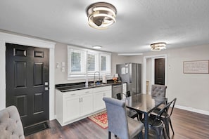 A modern kitchen with white cabinets, a black countertop, and stainless steel appliances.