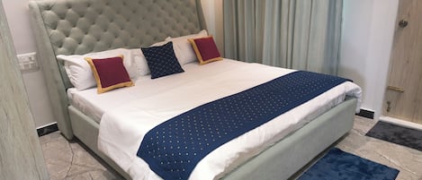 A hotel room with a large bed, a headboard, and a window with curtains.