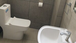 Casa de banho com sanita, lavatório e porta-toalhas.