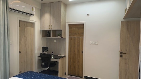 Una stanza compatta con un letto, una scrivania con una sedia, un armadio e l'accesso al bagno.