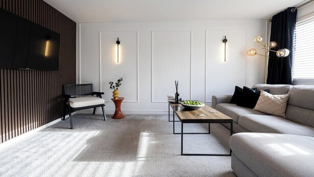 A modern living room with a sofa, a coffee table, a TV, and decorative wall lights. - Peaceful hideaway with Homely Comforts (Greater Manchester)