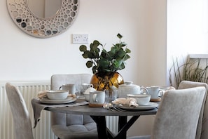 A dining table set with plates, bowls, and cups, surrounded by chairs.