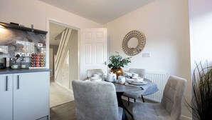 A modern kitchen with a built-in stove, a dining area with a table set for two, and a staircase leading to another level. - Peaceful hideaway with Homely Comforts (Greater Manchester)