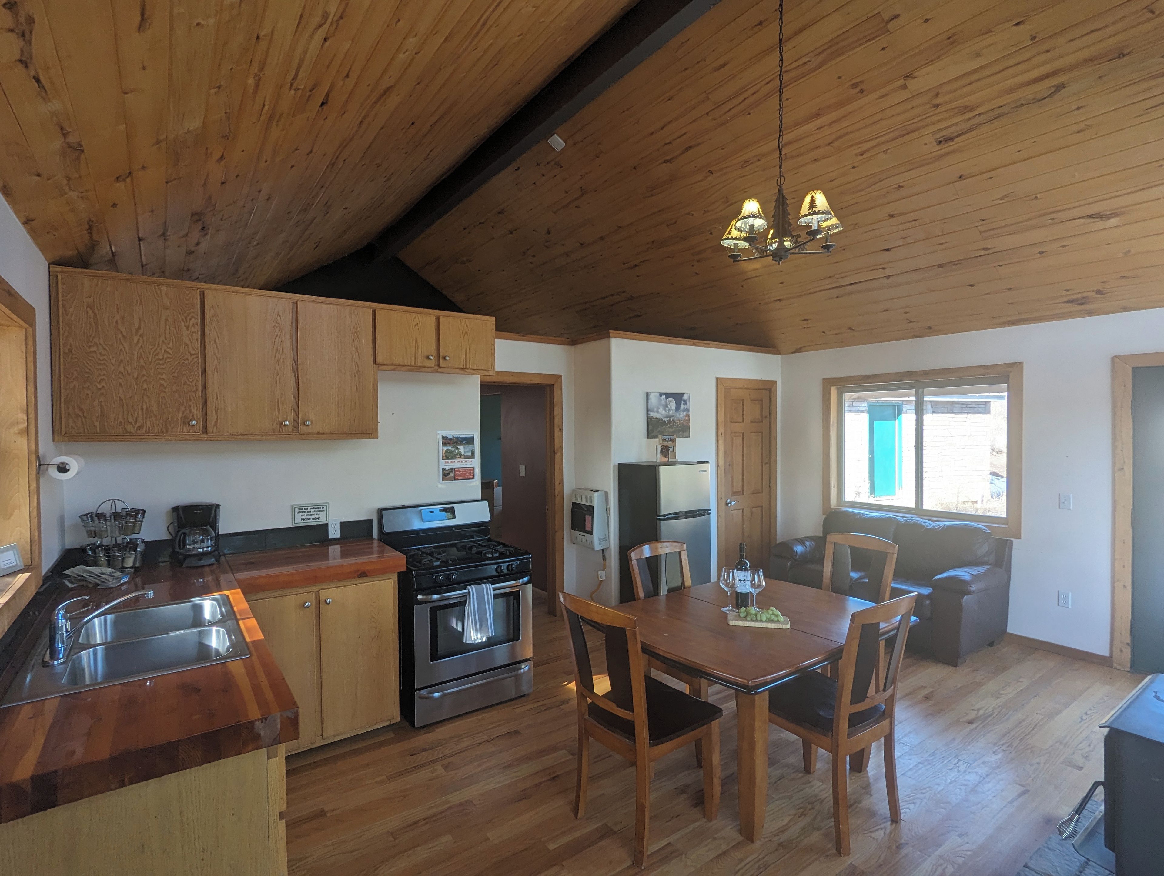 A kitchen with wooden cabinets, a stove, and a dining area with a table and chairs.