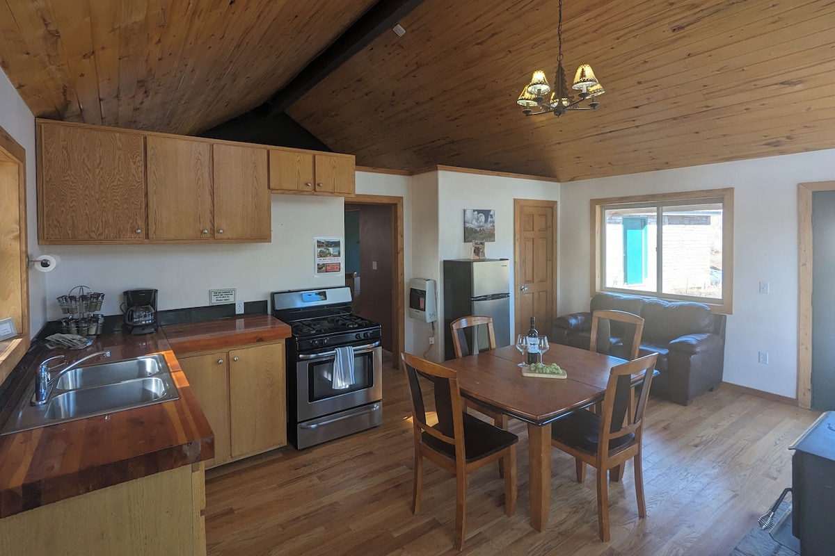 A kitchen with wooden cabinets, a stove, and a dining area with a table and chairs.