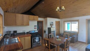 A kitchen with wooden cabinets, a stove, and a dining area with a table and chairs.