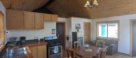 A kitchen with wooden cabinets, a stove, and a dining area with a table and chairs.