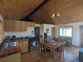 Una cocina con armarios de madera, estufa y comedor con mesa y sillas.