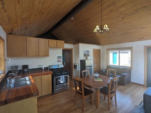 Una cocina con armarios de madera, estufa y comedor con mesa y sillas.