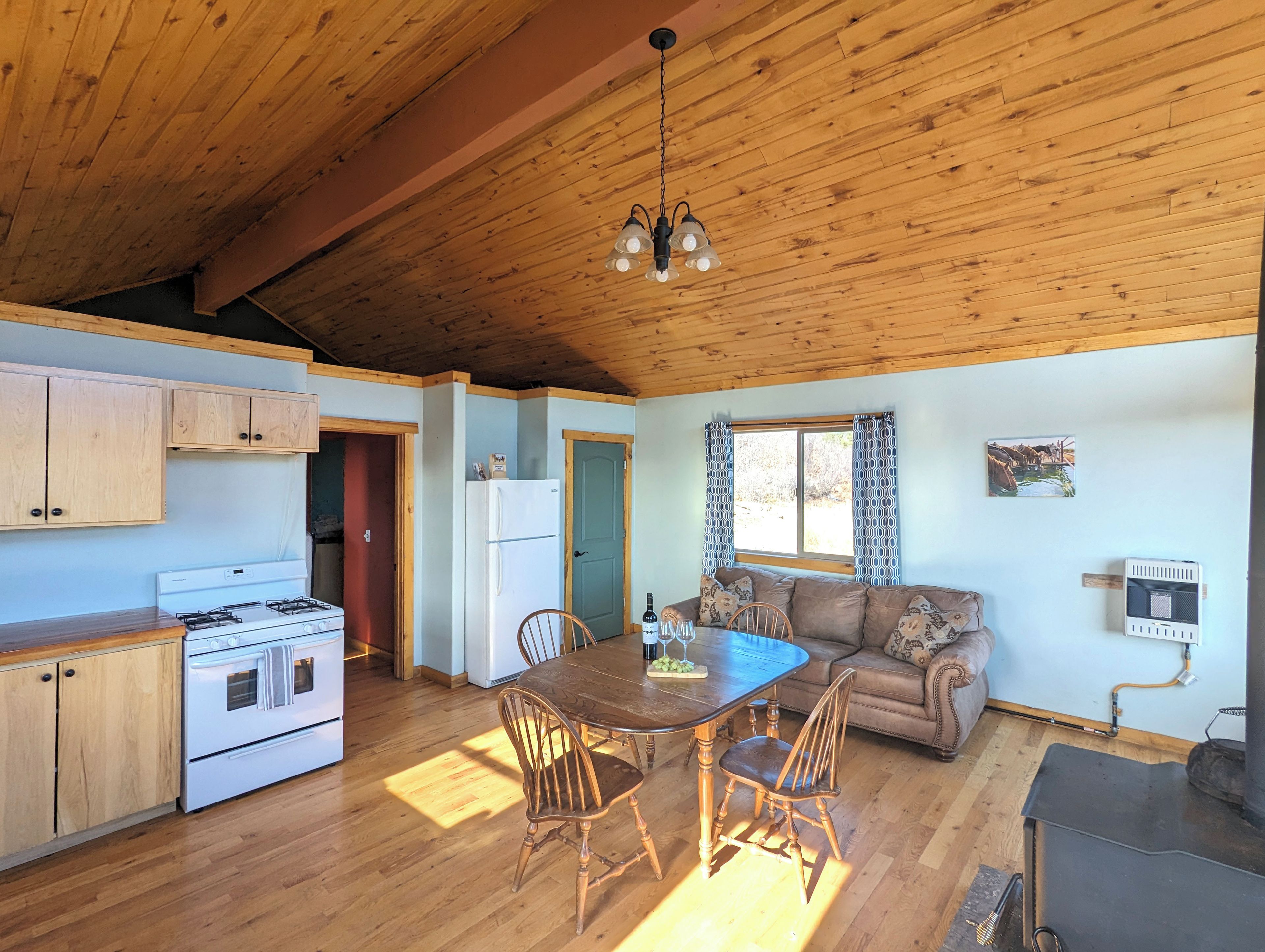 A cozy kitchen with wooden cabinets, a stove, and a dining area with a table and chairs.