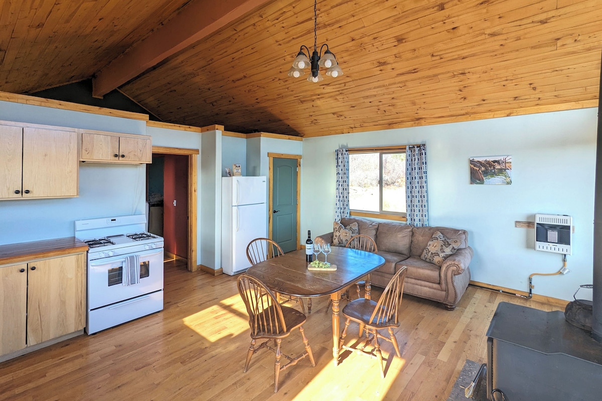 A cozy kitchen with wooden cabinets, a stove, and a dining area with a table and chairs.