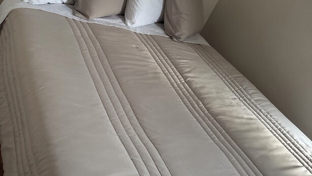 A neatly made bed with a quilted cover and several pillows. - Welcoming 2-bedroom building with AC in vibrant Chicago (Chicago)