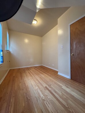 A room with wooden flooring, a door, and a window with blinds. - Welcoming 2-bedroom building with AC in vibrant Chicago (Chicago)