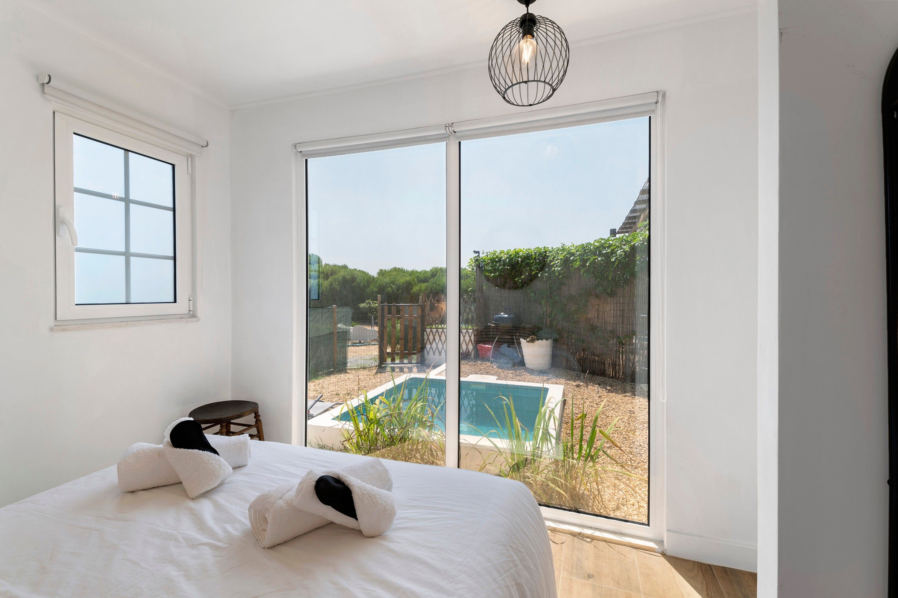 A bedroom with a large sliding glass door leading to a backyard with a pool.