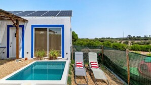 Une maison avec une piscine, des panneaux solaires et un jardin clôturé.