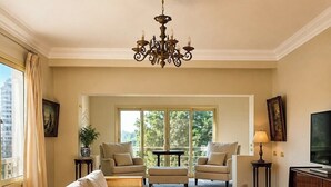 A spacious living room with a sofa, armchairs, a coffee table, and a television. - Royal Retreat in Dokki • Spacious with Nile View (Giza Governorate)
