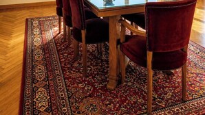 A dining room with a glass-top table, red upholstered chairs, a patterned rug, and artwork on the walls. - Royal Retreat in Dokki • Spacious with Nile View (Giza Governorate)