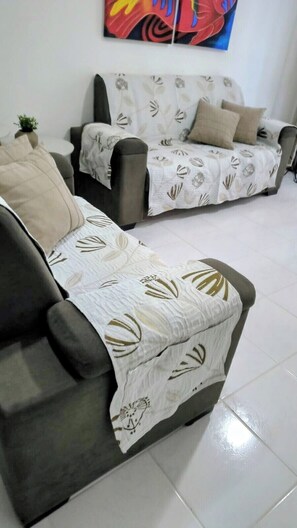 A living room with two sofas, one with a patterned throw and another with a plain cover.