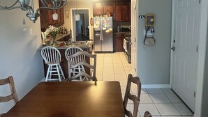 A dining area with a wooden table and chairs, a chandelier, and a kitchen in the background. - Charming 1-bedroom/bathroom in a home in Warner Robins (Warner Robins)