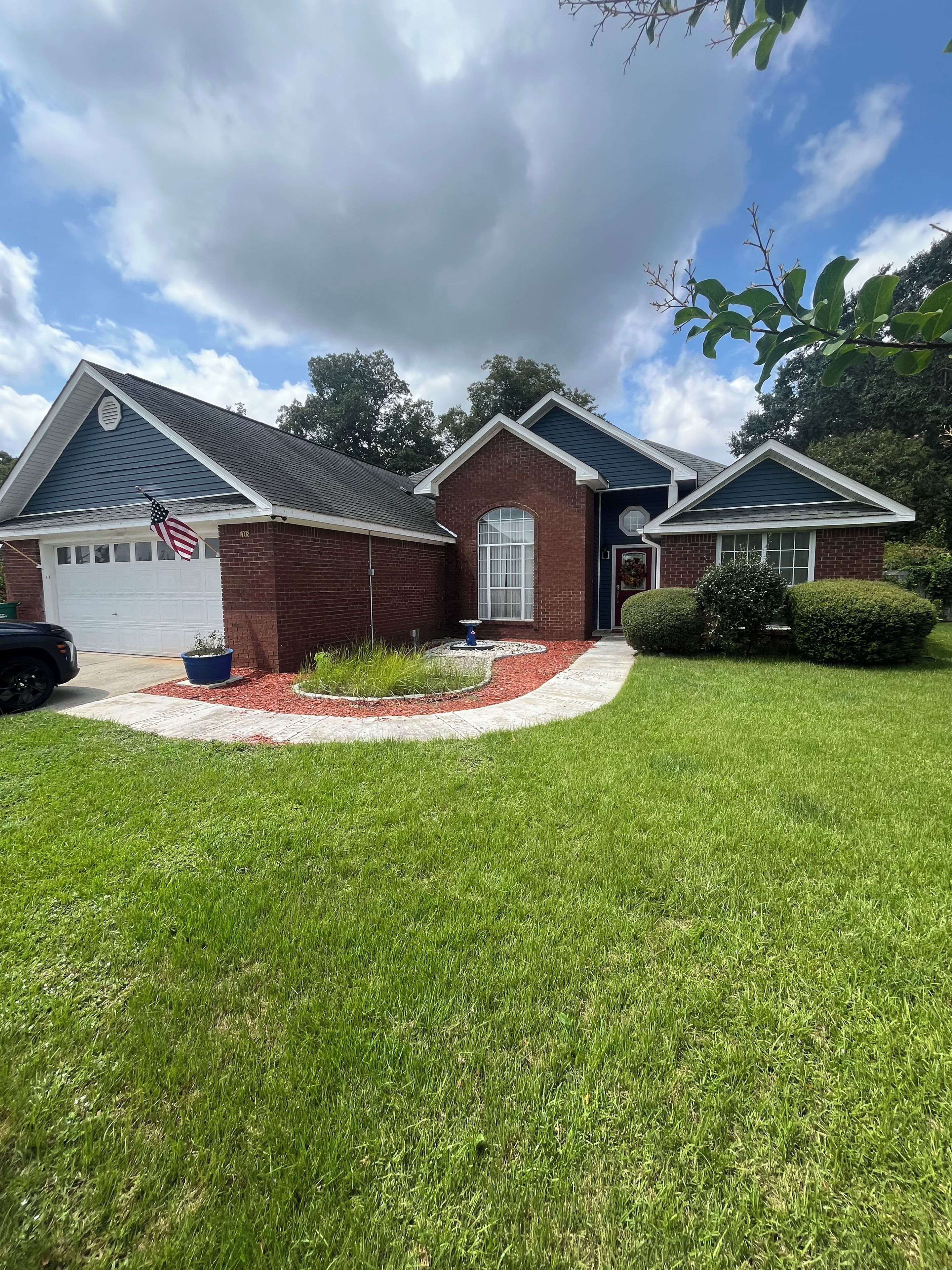 A two-story house with a brick facade, a garage, and a well-maintained lawn.