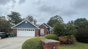 A residential property with a garage, a brick mailbox, and a well-maintained lawn. - Charming 1-bedroom/bathroom in a home in Warner Robins (Warner Robins)