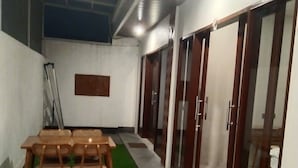 A room with a table and chairs, a green carpet, and a tiled floor. - Lily house bali (denpasar selatan)