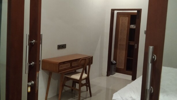 A bedroom with a wooden bed, a desk, and a chair. - Lily house bali (denpasar selatan)