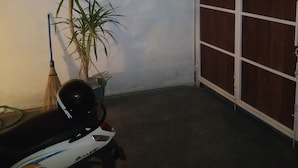 A covered outdoor area with a scooter, a broom, and a potted plant. - Lily house bali (denpasar selatan)