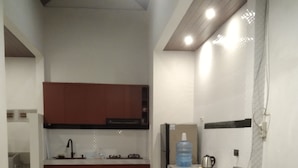 A compact kitchen with a refrigerator, a water dispenser, and a coffee maker. - Lily house bali (denpasar selatan)