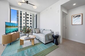 Una sala de estar moderna con un televisor de pantalla plana, un sofá, una mesa de centro y una planta.