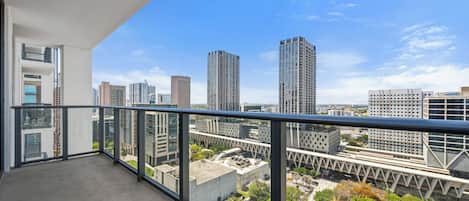 A balcony with a city view overlooking high-rise buildings.