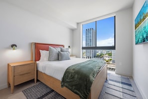 A modern bedroom with a large window, a bed with a red headboard, and a city view. - The Crosby 2BR Luxury Palermo Home (Miami)