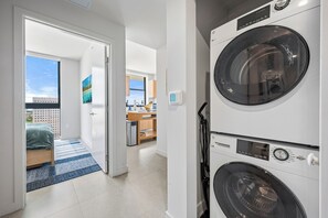 A laundry room with stacked washing machines, a kitchen area, and a view of a balcony. - The Crosby 2BR Luxury Palermo Home (Miami)