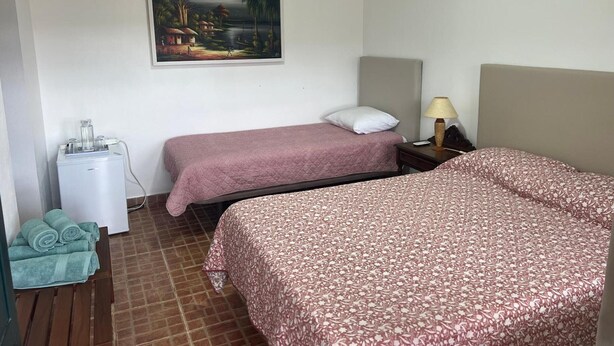 A hotel room with two beds, a painting on the wall, a bedside table with a lamp, and a water dispenser. - Apartment 'Quarto 7' with Wi-Fi and Air Conditioning (Corte do Pinto)