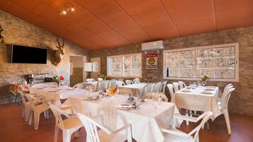 Ein Restaurant mit Steinwänden, Holzbalkendecke und mehreren gedeckten Tischen.