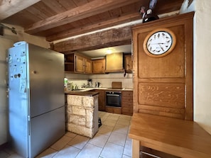 Eine Küche mit Holzausstattung, einer eingebauten Kochinsel und einem Kühlschrank.