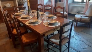 Ruokailuhuoneessa on puinen pöytä, johon on katettu kuudelle henkilölle, ja pöydän ympärillä on puisia tuoleja.