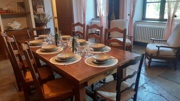 A dining room with a wooden table set for six, surrounded by wooden chairs.