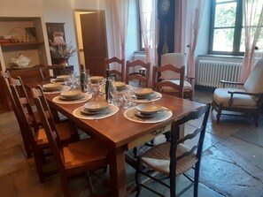 Uma sala de jantar com uma mesa de madeira posta para seis pessoas, rodeada por cadeiras de madeira.