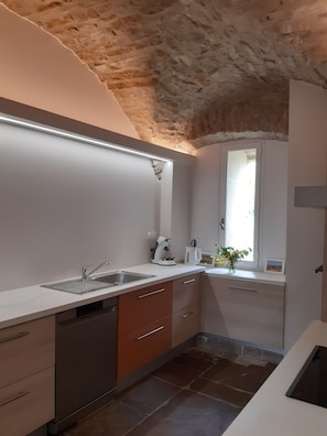 A modern kitchen with a built-in dishwasher, a coffee machine, and a window with a view.