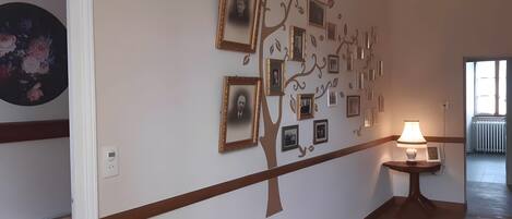 A hallway with a wall decorated with framed photos arranged in a tree-like pattern.