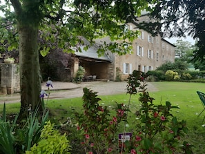 A building with a stone facade, a covered patio, and a grassy courtyard.