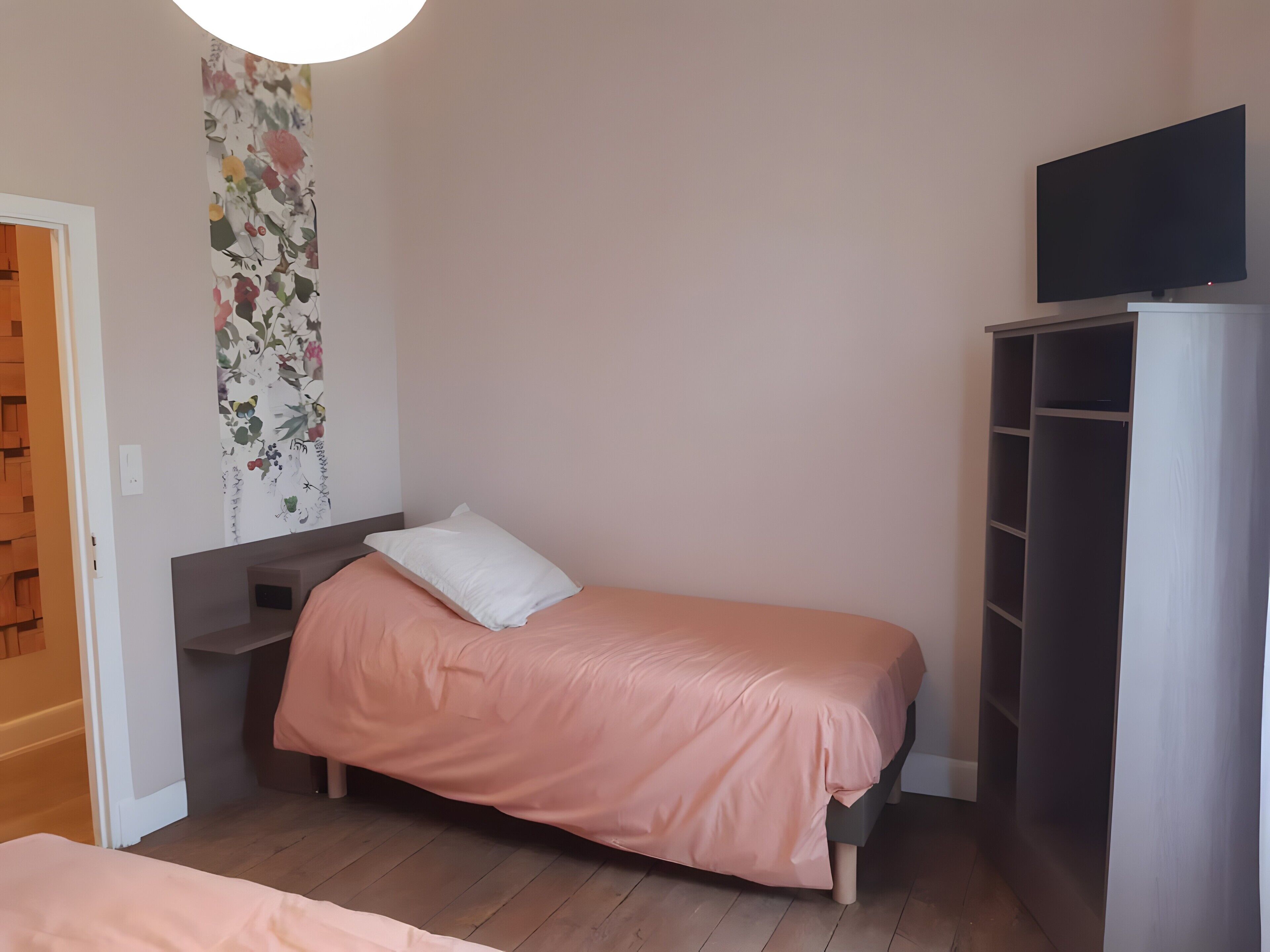 Une chambre avec un lit simple, une armoire et un téléviseur.