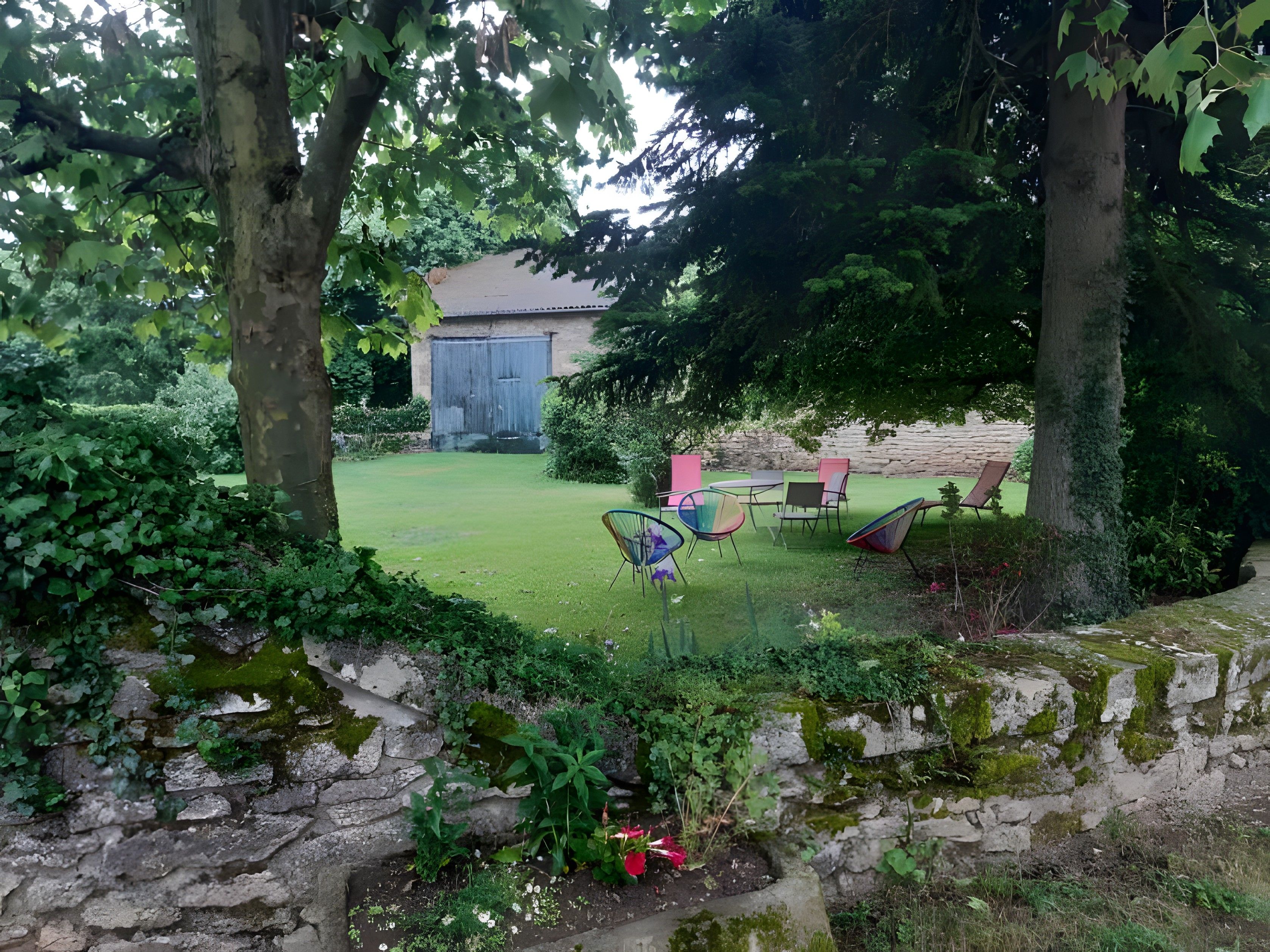 Een tuin met een stenen muur, een gazon en tuinmeubilair.